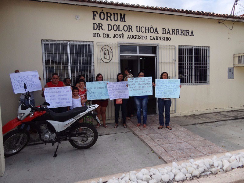 Seis mulheres segurando cartazes em frente ao edifício do Fórum do município