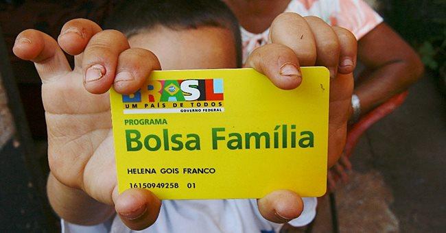 Criança segurando cartão do Bolsa Família