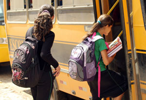 Meninas com mochila e livros entrando em ônibus escola