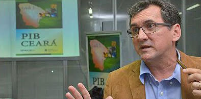 Flávio Ataliba em primeiro plano e ao fundo banner e tv com letreiro PIB Ceará