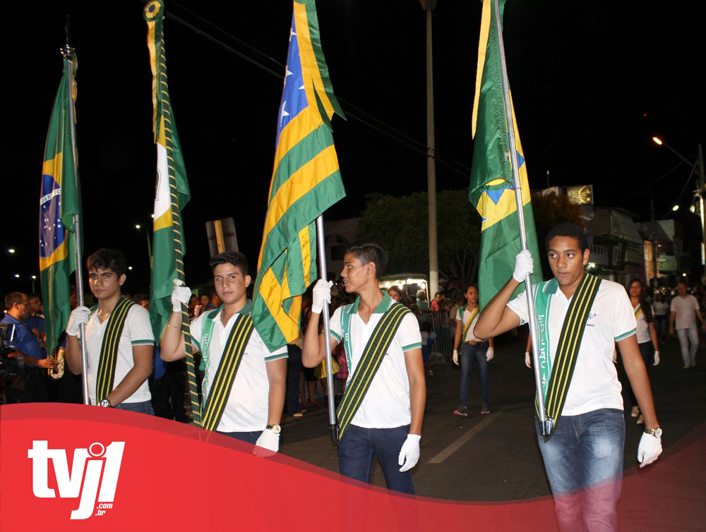 Quatro jovens em desfile segurando bandeiras.