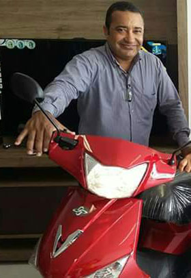Ostiano Barbosa em pé ao lado de uma motocicleta.