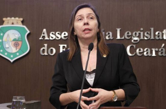 Rachel Marques falando ao microfone. Ao fundo brasão do Estado do Ceará e letreiro da Assembléia Legislativa do Estado do Ceará