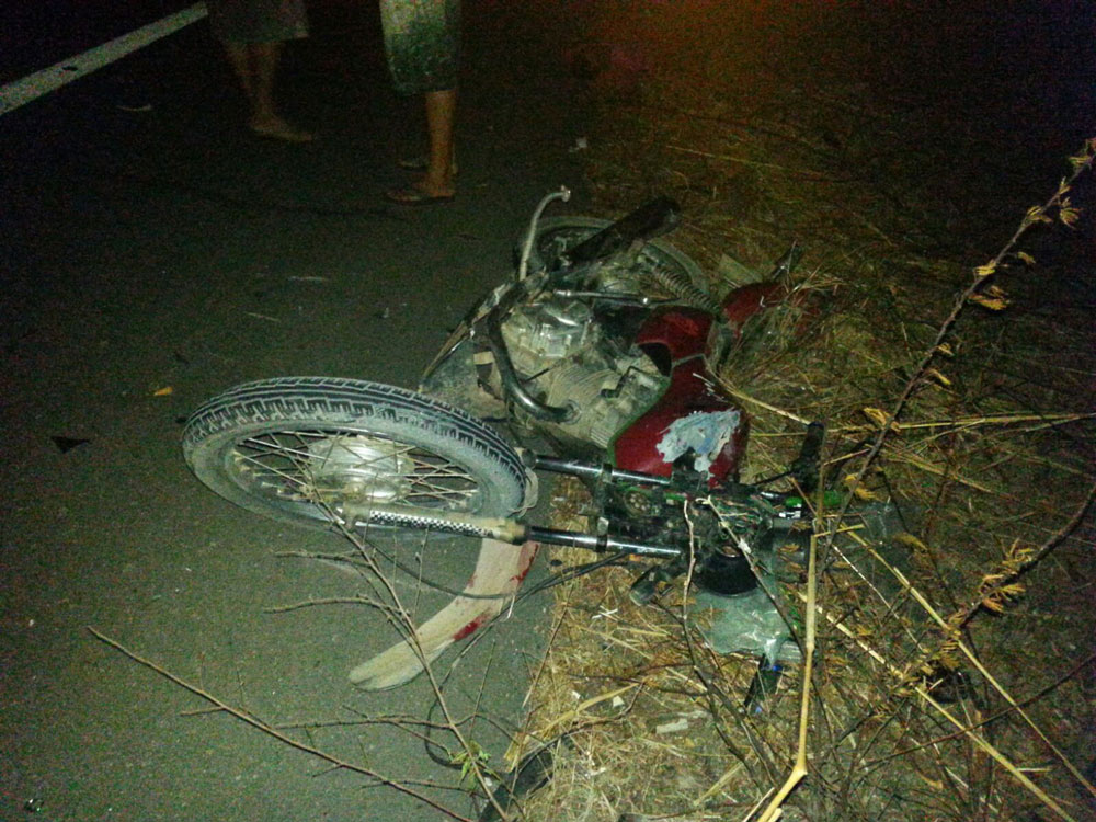 Motocicleta danificada e caída a margem da rodovia.