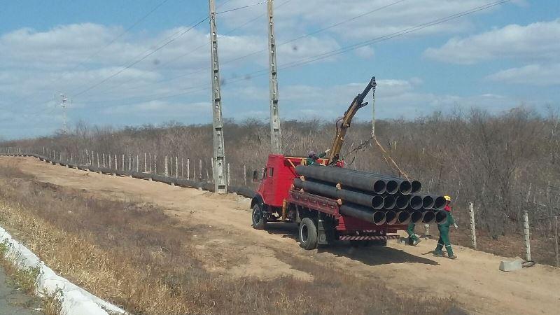 Caminhão carregado de grandes tubos de encanamento em estrada de terra