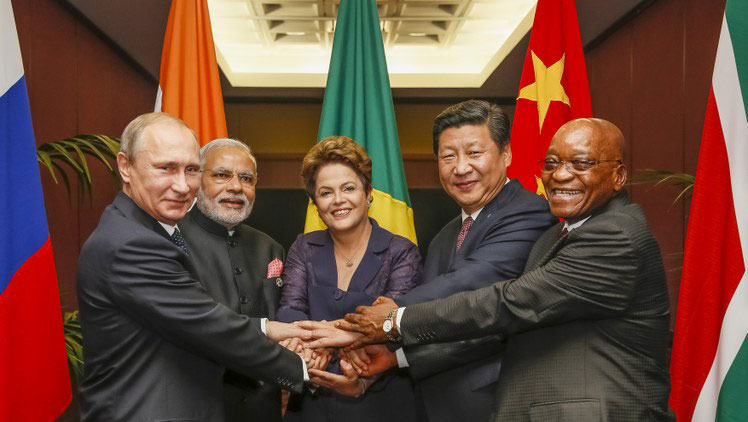 A presidenta do Brasil Dilma Russeff ao centro mais quadro presidentes posicionados igualmente ao seus lados, posando para foto com as mãos unidas a frente.