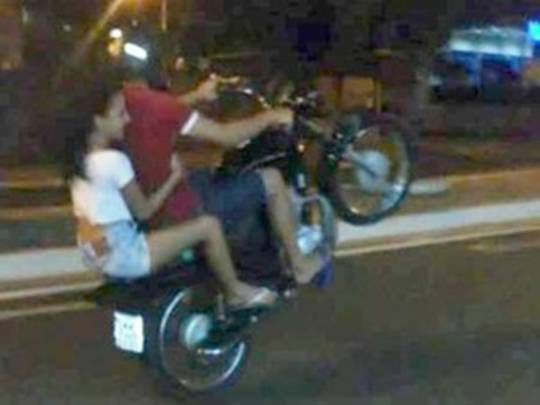 Dois jovens empinando moto.