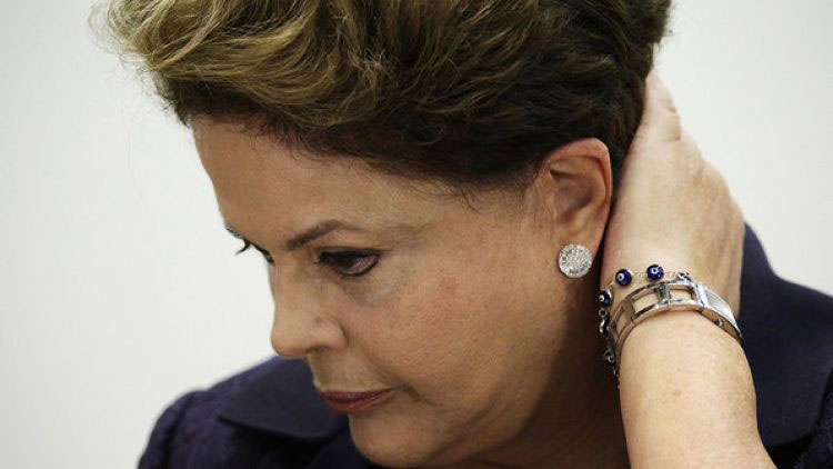Presidente Dilma com olha baixo e com uma das mãos na nuca