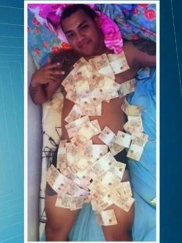 Homem deitado com cédulas de R$ 50 reais espalhados pelo corpo
