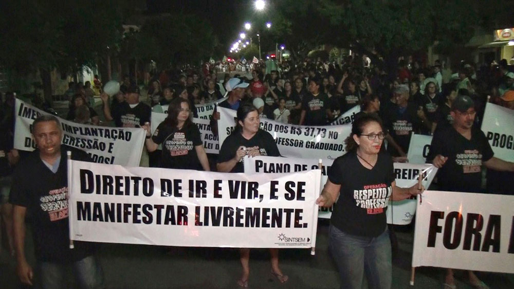 Pessoas vestindo preto segurando faixas em protesto