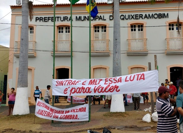 Pessoas com faixas protestando em frente ao prédio da prefeitura municipal de Quixeramobim.