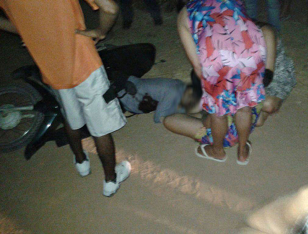 Corpo de Ostiano Barbosa caído ao chão com pessoas em volta.