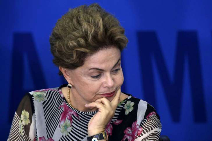 Dilma Rousseff com a mão no queixo e olhando para baixo