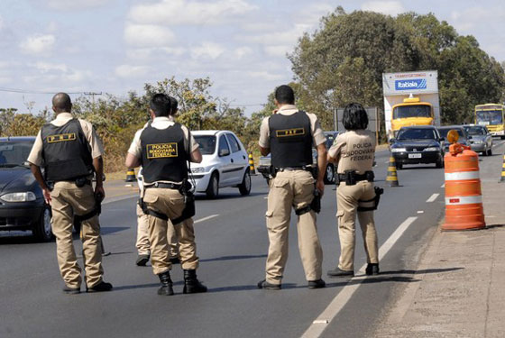 Cinco Policias em uma das mãos de uma rodovia e veículos transitando na outra