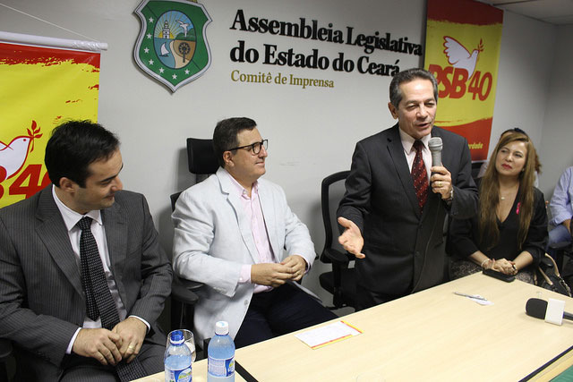 Heitor Férrer falando ao microfone em Assembleia Legislativa do Estado do Ceará com banners do PSB ao fundo