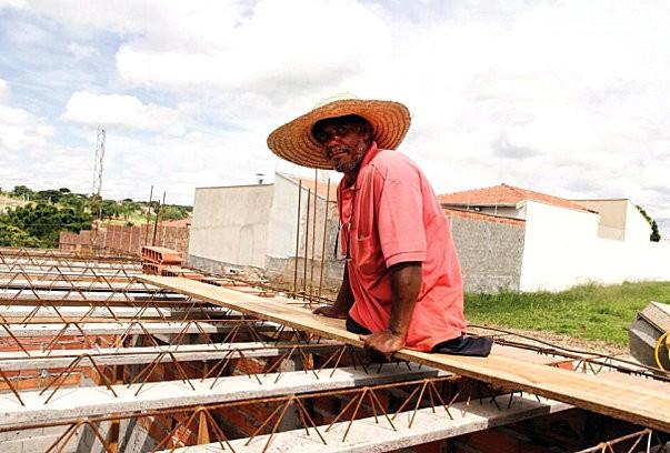 Delfino Lima de Jesus com chapéu de palha trabalhando na construção da laje de uma residência