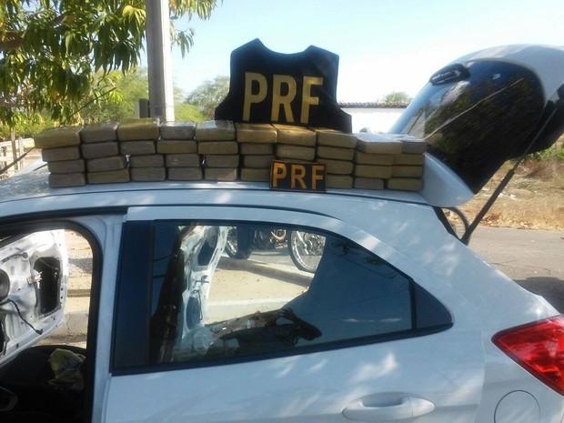 Pacote com drogas sobre o telo de automóvel com colete policial da PRF