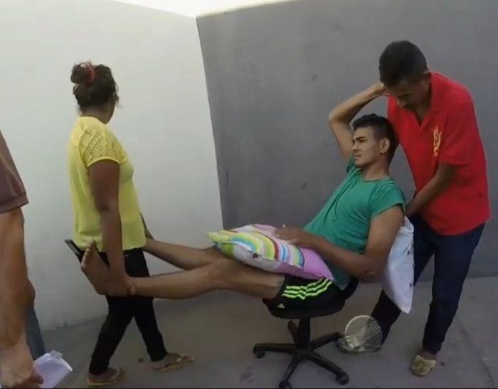 Robson Diego, baleado, sendo levado em cadeira de rodinhas por familiares