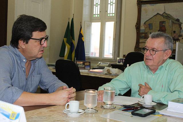 Danilo Forte  e Henry Campos setados a mesa, conversando
