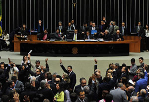 Senado brasileiro com vários políticos, onde alguns estão sinalizando voto com a mão erguida